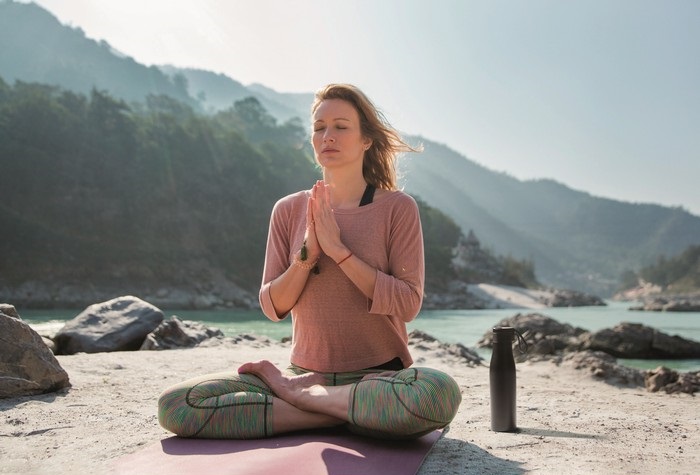 Woman Meditating While Sitting Next To The River